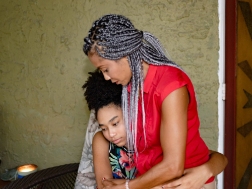A woman comforts and hugs her daughter at their home. Her daughter has expressed suicidal thoughts, and she is trying to figure out what to do and how to help.