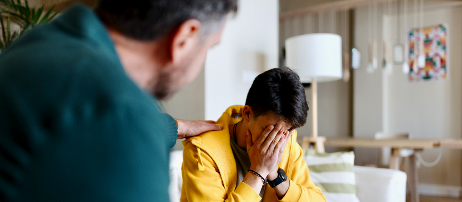 A man comforts his son at their home. His child has expressed suicidal thoughts.