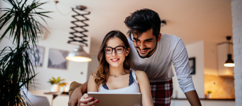 A young couple in their living room on a computer. They are discussing healthy boundary setting in relationships.