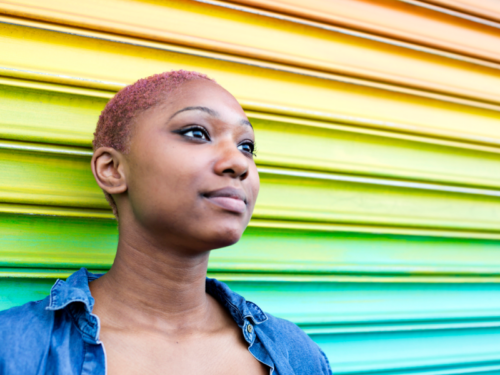 Teen standing against a rainbow colored wall