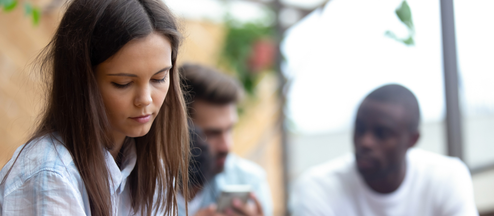 A young woman is at a coffee shop with her friends. She has social anxiety.