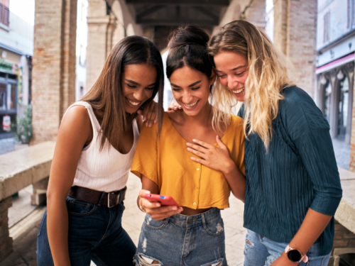 Friends looking at their phone on their college campus