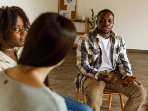A young male sits in a support group. He is gaining support and education on how to help someone with a dissociative disorder.