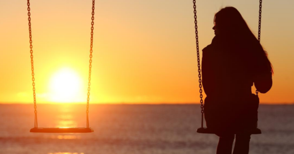 Woman sitting on swings by herself looking lonely