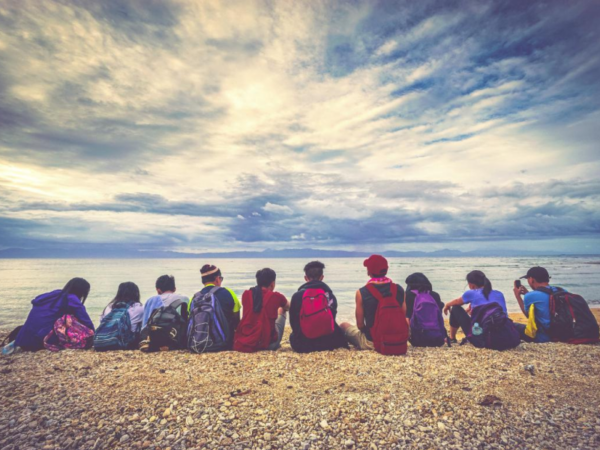 Teens sitting on a beach looking out into the ocean