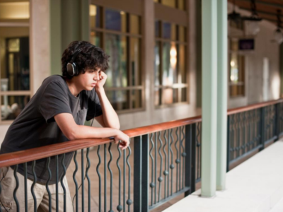 Teenage boy with depression leaning on a rail while contemplating life