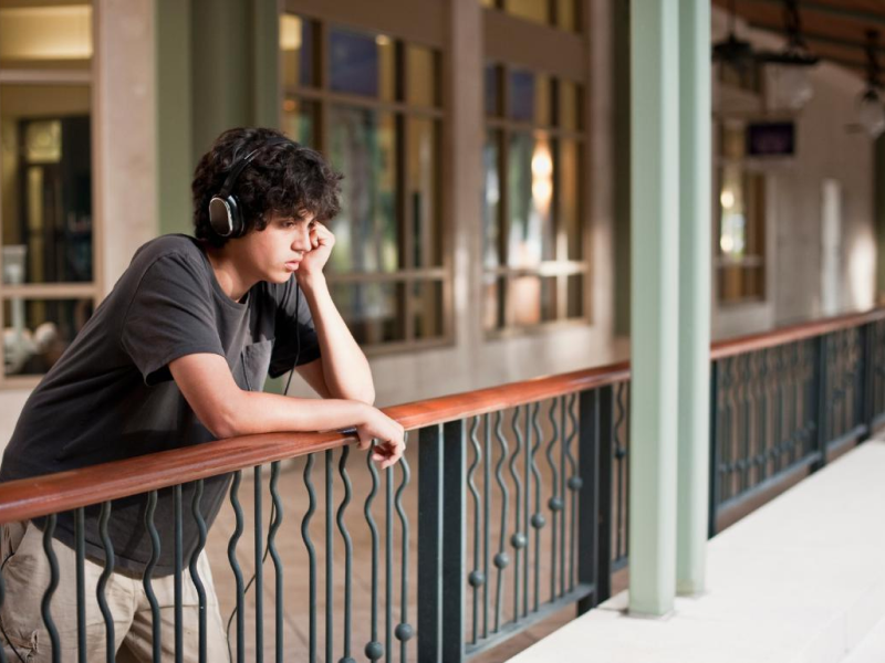 Teenage boy with depression leaning on a rail while contemplating life