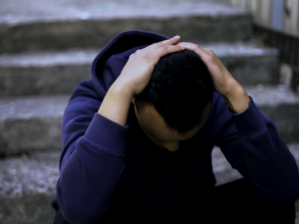 A young man struggling with vaping and nicotine withdrawal plus depression sits on steps alone