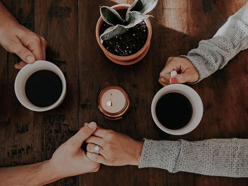 Parents holding hands while drinking coffee