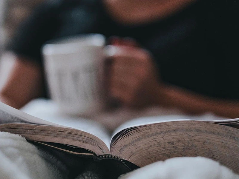 Person reading a book while enjoying coffee