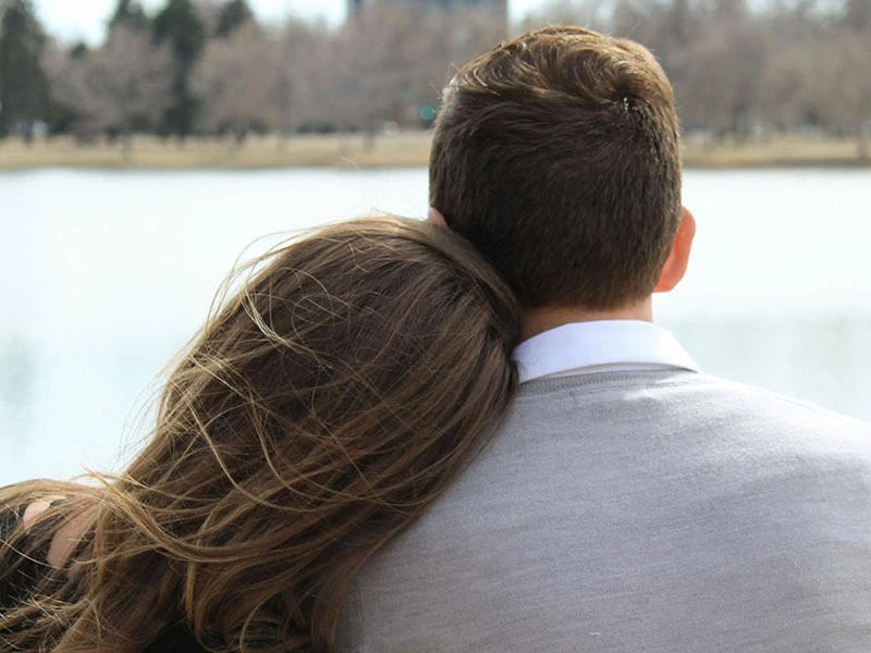 Teenage couple staring at a pond in the distance