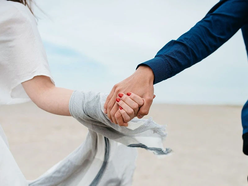 Couple holding hands on the beach