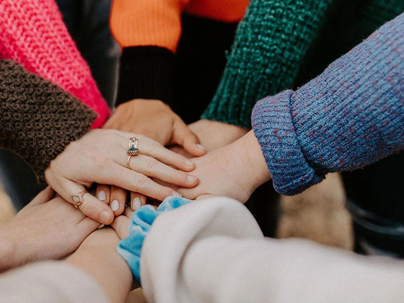 group of teens putting their hands together for team building activity