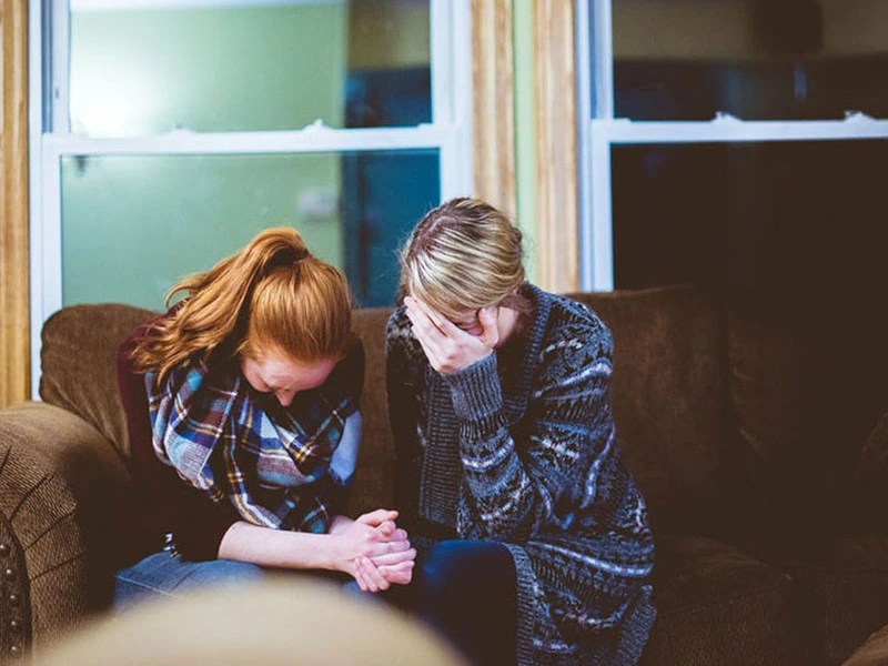 Two woman crying mourning the loss of a loved one