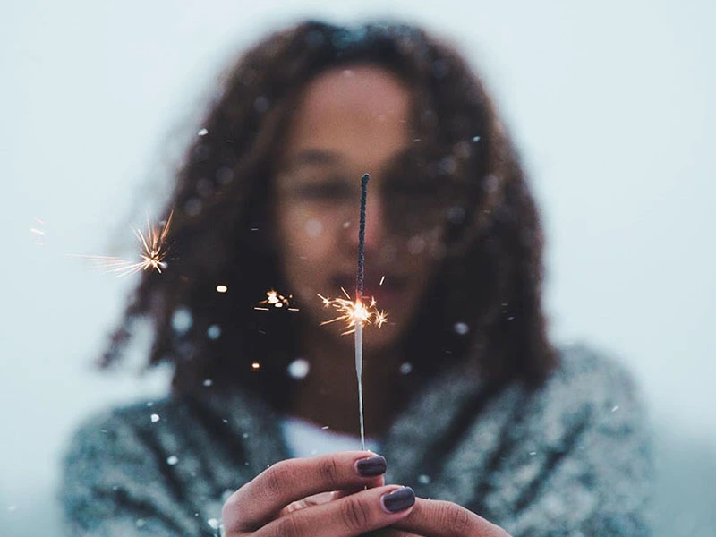 Woman using a sparkler on a snowy winter day
