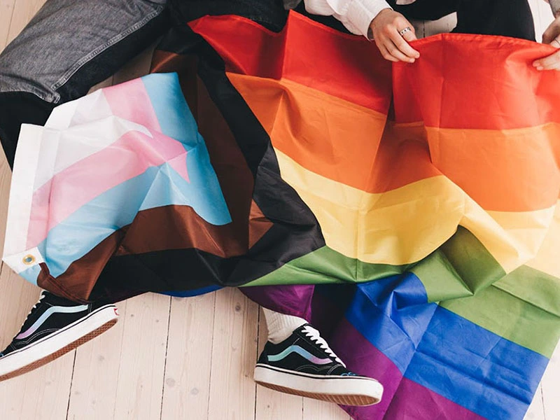 two people putting up a progressive pride flag