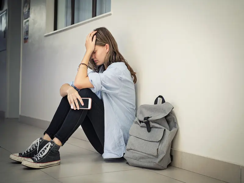 Teenage crying in a hallway alone because she is being bullied