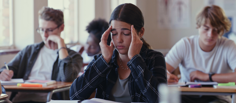 A teen girl sits in a classroom struggling with a panic attack
