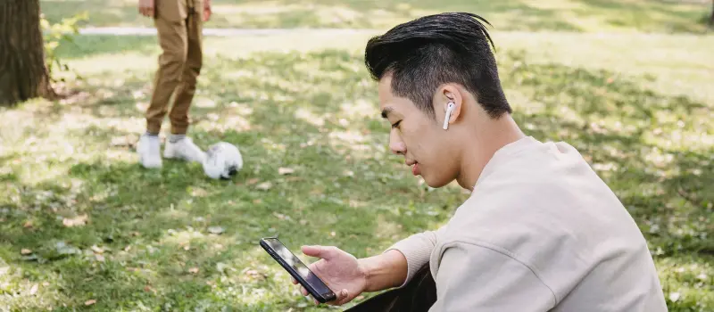 Young adult male taking a call with family in the park