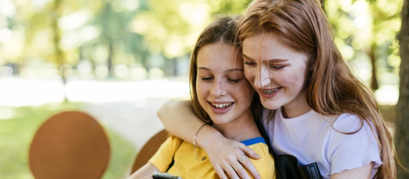 Teen friends with secure attachment styles hug each other