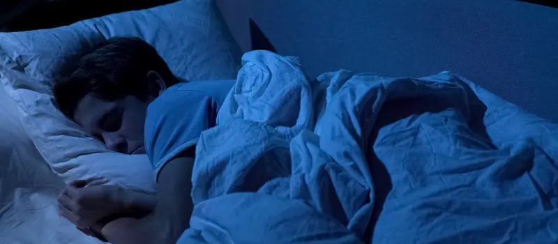 A depressed young man struggles to go to sleep in bed at night