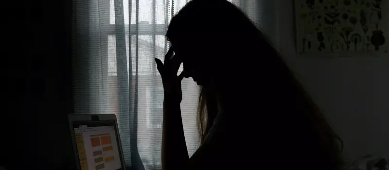 Teen girl in a dark room staring at her computer struggling with depression