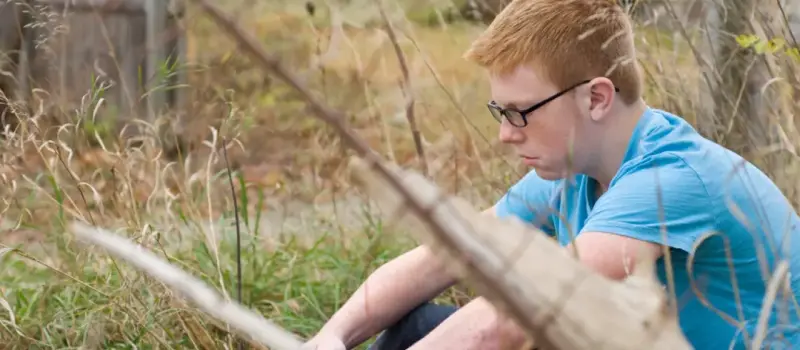 Teen boy sitting outside struggling with his mental health