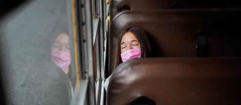 Teen girl on a school bus trying to sleep