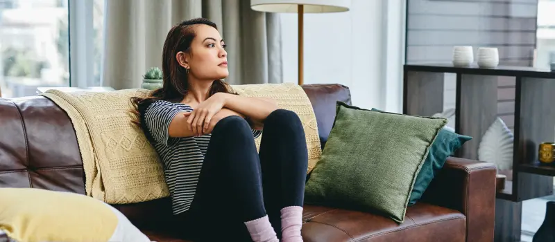 A young woman processes trauma while sitting on her couch