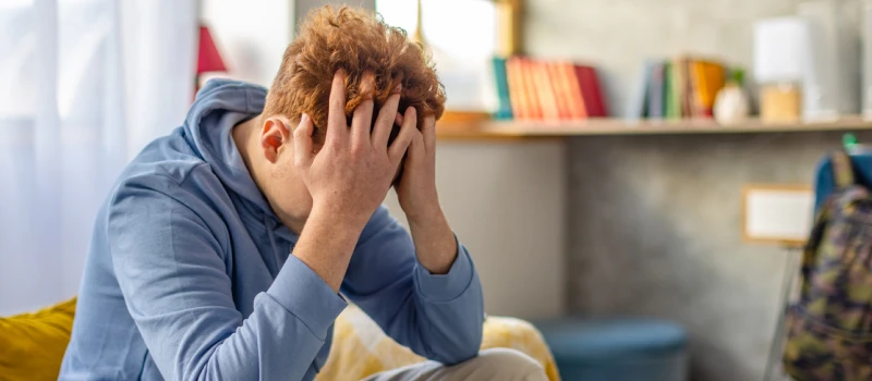 A young man with red hair sits on his couch trying to process trauma