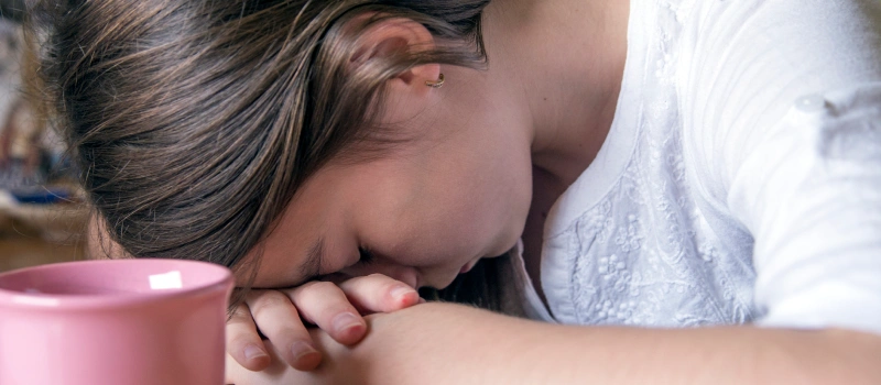 A young girl sits with her head on her hands dealing with trauma