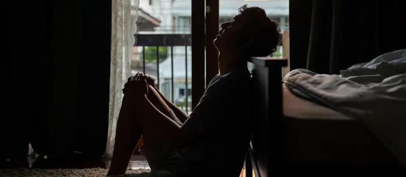 A young man with complex trauma sits on the floor of his bedroom 