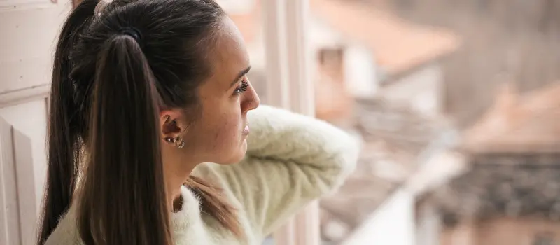 A teen girl dealing with social anxiety looks out of her window