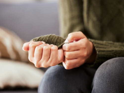 A picture of a person's hands picking at their fingernails because they are afraid of people