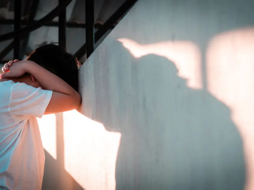 A young man dealing with secondary trauma leans against a wall