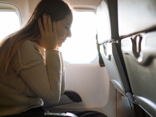 A young woman is sitting on an airplane dealing with situational anxiety