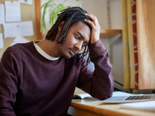 A young adult male is self gaslighting while sitting at a desk