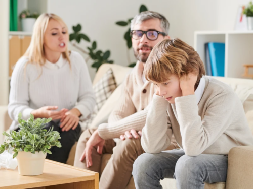 A young teen boy deals sits with his parents who are not taking care of his needs