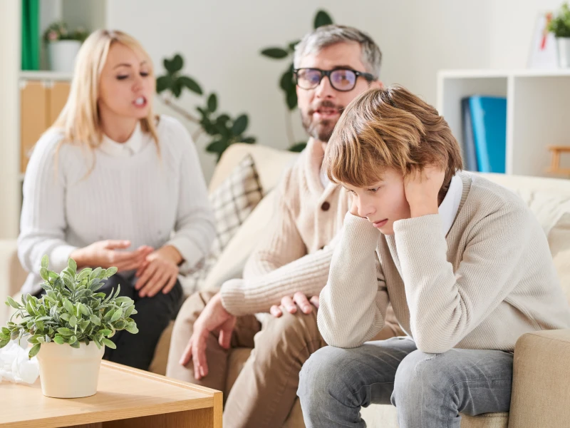 A young teen boy deals sits with his parents who are not taking care of his needs