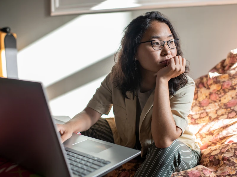 A teen girl in glasses sits at her computer dealing with anxiety