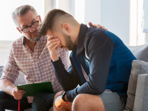 A young adult male dealing with trauma and ptsd is comforted by his therapist.