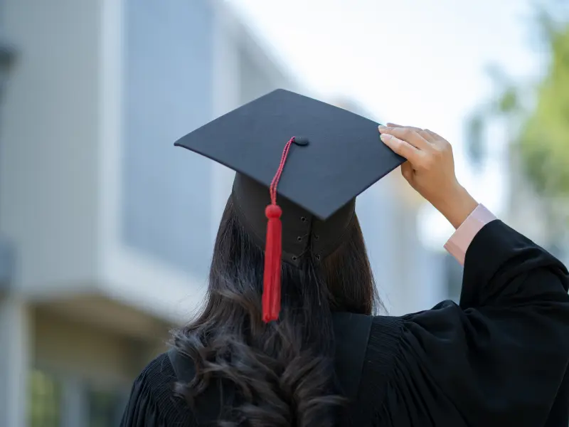 A recent college graduate in a cap and gown wonders how her mental health will be impacted
