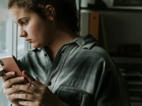 A teen in a plaid shirt stares out of the window