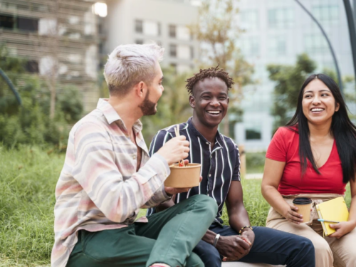 A chosen family of three teen friends sit together smiling