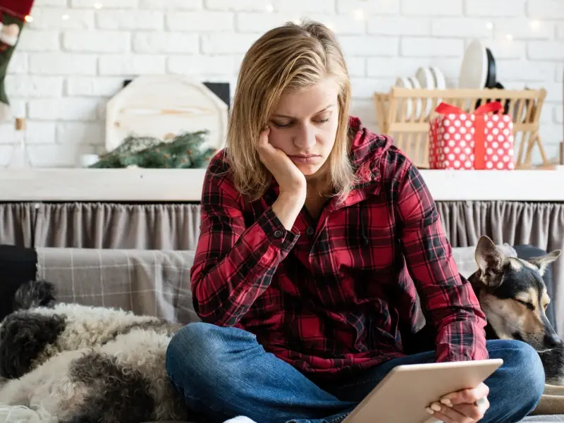 A young woman in a plaid shirt is sad about the holidays