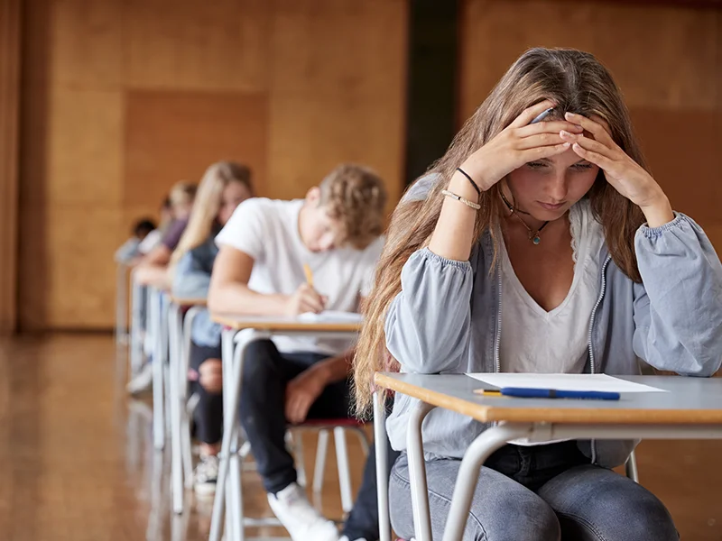 An anxious female college student sits at her desk in class