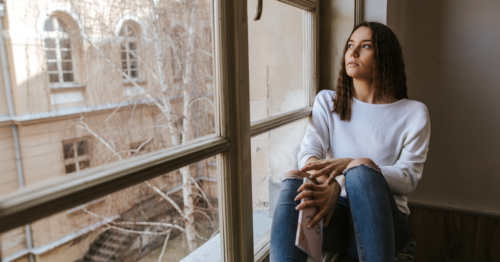 A socially isolated young adult looks out of her window