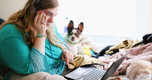 Teen struggling with mental health challenges sits on a laptop during an online therapy session.