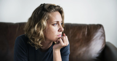Woman sitting on a couch alone zoning out