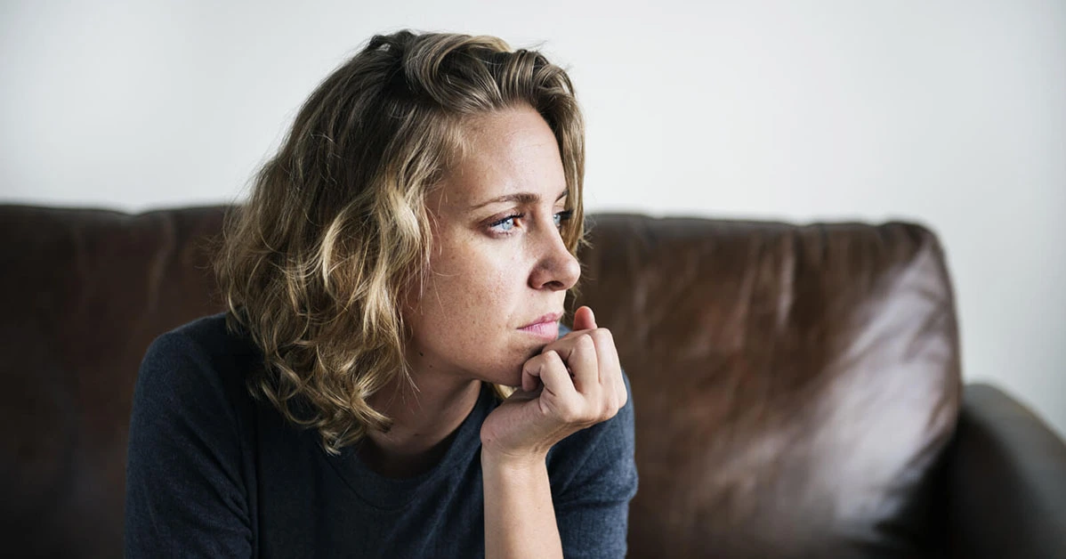 Woman sitting on a couch alone zoning out